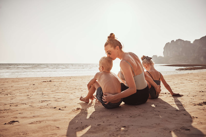 Mother kissing kids sitting on a beach
